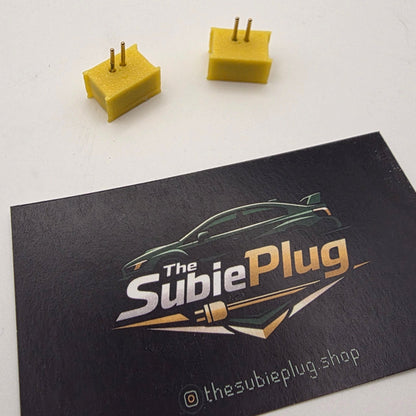 Yellow plugs on a black card with 'The Subie Plug' logo on a white background